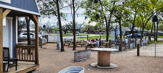 Liberty Tavern Liberty Hill Outdoor Beer Garden and Patio Outdoor dining area at Liberty Tavern in Liberty Hill with picnic tables and wooden spool tables on a gravel patio.